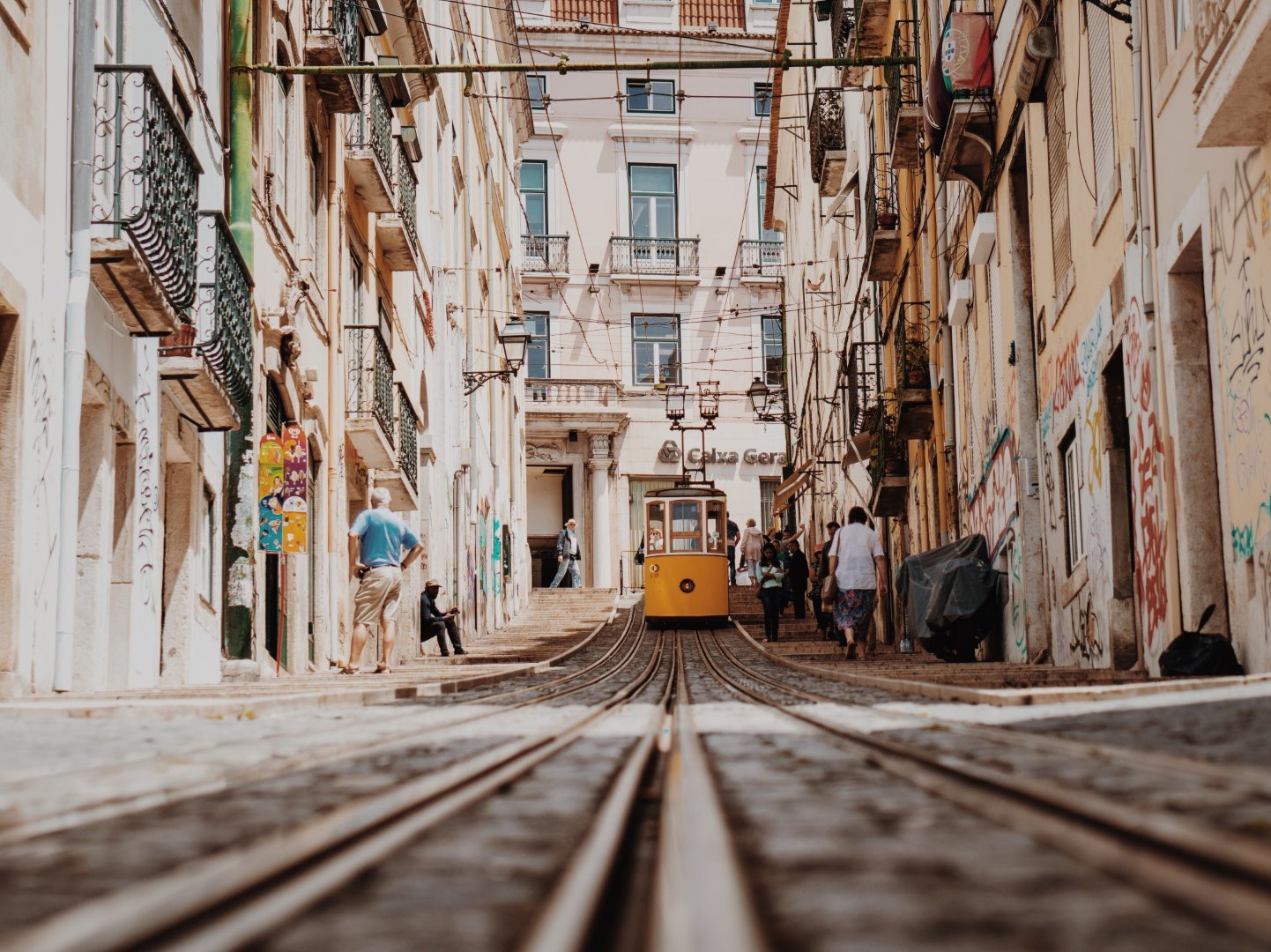 imagem de capa do artigo: 7 Razões para Visitar Portugal em 2023. Na imagem está o elevador da Bica, em Lisboa com pessoas a passar ao lado do mesmo.